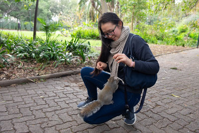 Portrait of squirrel climbing on a kneeling woman with scarf and handbag 