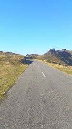 Country road against clear blue sky