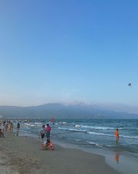 People on beach against clear sky