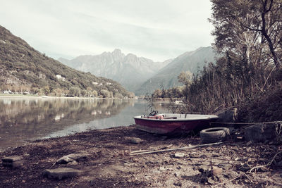 Boat moored on lake against sky