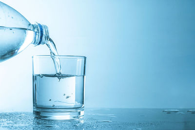 Close-up of glass of water against blue background