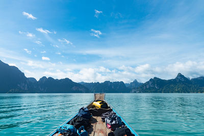 Backpacks on rowboat in lake against mountains and sky