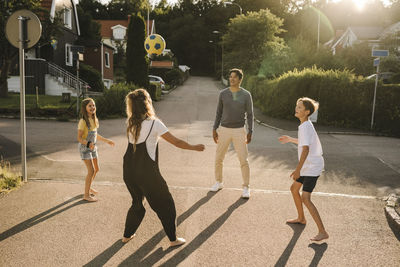 Happy family playing with soccer ball on road