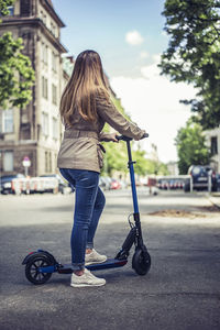 Rear view of woman skateboarding on road