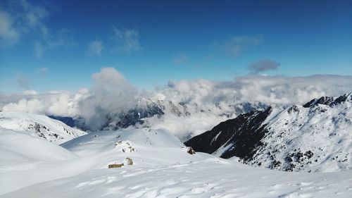 Scenic view of snow covered mountains against blue sky