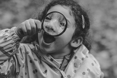 Close-up of girl with mouth open holding magnifying glass