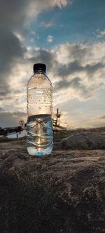 Water bottle on land against sky during sunset