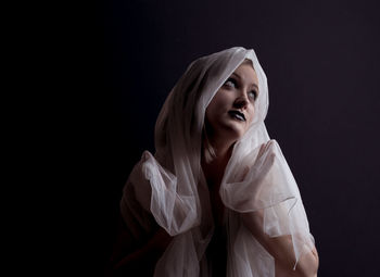 Woman looking up against black background