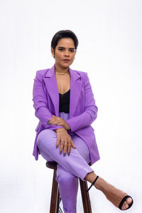 Confident pretty business woman being ready to work. she is sitting on a wooden stool