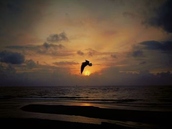 Silhouette man jumping at beach against sky during sunset