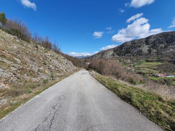 Road leading towards mountains against sky