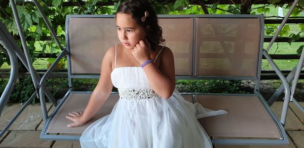 Thoughtful girl looking away while sitting on porch swing