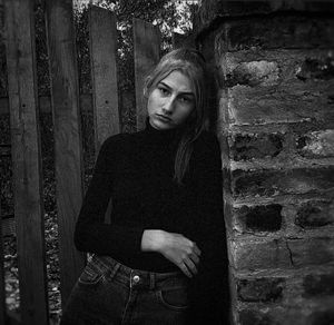 Portrait of young woman standing against wall