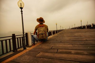 Rear view of woman standing on pier against sky