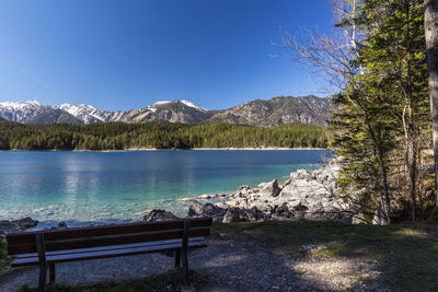 Scenic view of lake by mountains against clear blue sky