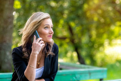 Young woman looking away while sitting outdoors