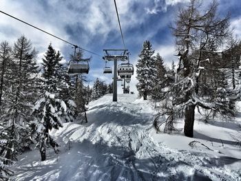 Low angle view of ski lift over snowy field against sky