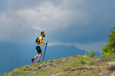 Side view of man climbing on mountain against sky