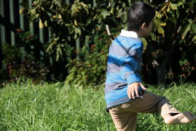 Rear view of boy playing in grass