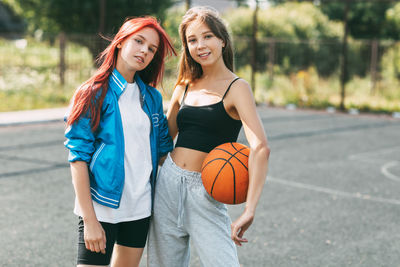 Portrait of two charming girls with a basketball on the sports field. friendship, best friends