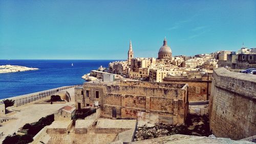 View of sea and buildings against blue sky