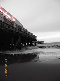 Low angle view of illuminated text on beach against sky