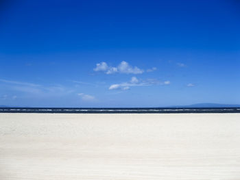 Scenic view of beach against blue sky