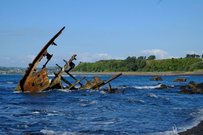 Abandoned boat in sea against sky