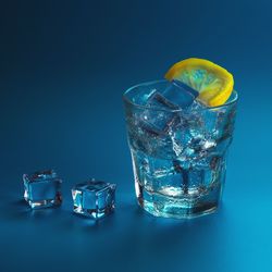 Close-up of drink glass on table against blue background