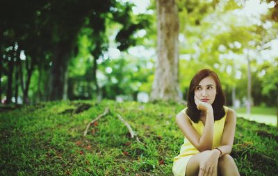 Thoughtful beautiful young woman sitting at park