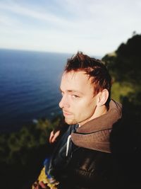 Portrait of young man looking away against sea