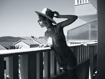 Young woman leaning on railing and looking down at balcony