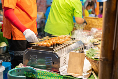 Grilled sausage on the flaming grill in street food market.