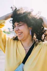 Happy woman with hand in hair on sunny day