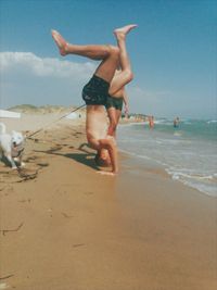 Full length of shirtless boy on beach against sky