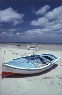 Boat moored on beach against sky