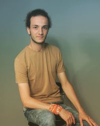 Portrait of young man standing against wall