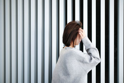Side view of young woman standing against wall