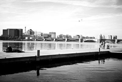 Bridge over river by buildings against sky