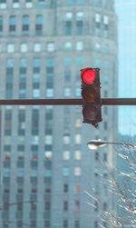 Close-up of red traffic light against buildings in city