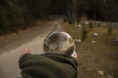 Cropped hand of person holding crystal ball on land