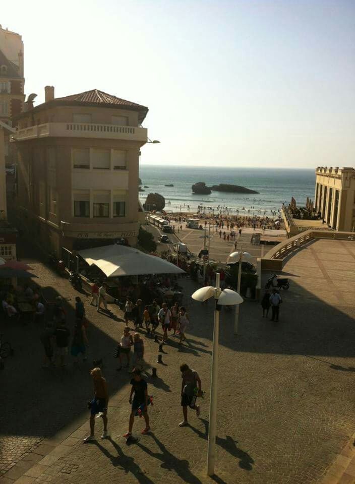 PEOPLE WALKING ON BEACH AGAINST CLEAR SKY IN CITY