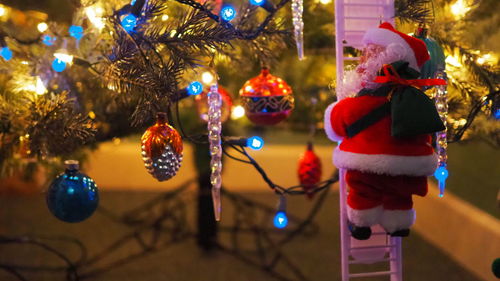 Close-up of christmas tree, santa on a ladder under the tree.