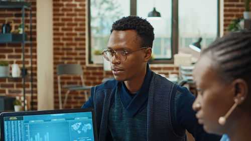 Side view of young man using mobile phone in office