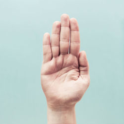 Cropped hand gesturing against turquoise background