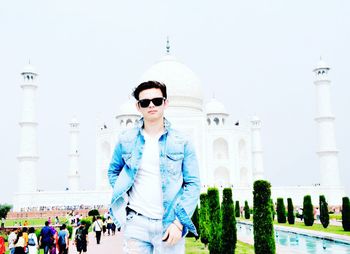 Man wearing sunglasses standing against built structure