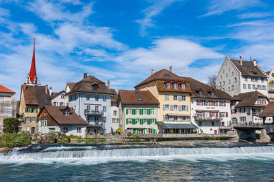 Buildings in city against cloudy sky