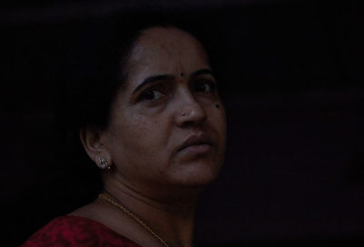 Close-up of young woman against black background