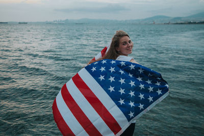 Portrait of smiling woman in sea with american flsg