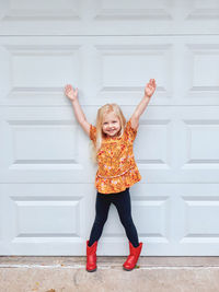 Portrait of smiling girl standing against wall